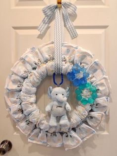 a baby shower wreath with a teddy bear hanging from it's side on the front door