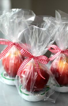 three apples wrapped in plastic sitting on top of a table