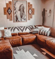 a living room with brown leather couches and native art on the wall above it