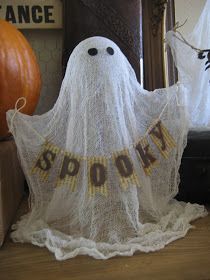 a white ghost statue sitting on top of a wooden table next to a pumpkin and other decorations