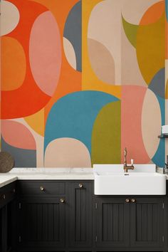 a kitchen with black cabinets and an abstract painting on the wall behind the sink area