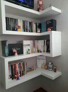 a corner book shelf with books on it and a flat screen tv above the shelves