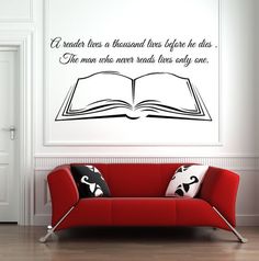 a red couch sitting in front of a white wall with a book on it's back