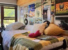 a bed sitting in a bedroom next to a window with lots of pictures on the wall