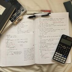 a calculator sitting on top of a book next to a pen and pencil