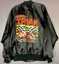 "This vintage 1990s Ernie Irvan black satin jacket is bomber style. It has knit collar, cuffs and waist band. Across the top front left is says Ernie Irvan #28. This jacket has a 7 snap front and pockets on either side.  Across the back it says Ernie Irvan, the two iconic black and white checked flags and a heavily logoed race car. The tag in the back says Auburn Sportswear, Made in USA, L. Measurements for this jacket when laying flat are: Snap front is 26\" long. The sleeves (measured from the Retro Black Crew Neck Outerwear, Black Retro Outerwear With Crew Neck, Vintage Black Crew Neck Outerwear, 80s Outfit, Satin Jacket, Satin Jackets, Lovely Dresses, Race Car, Auburn