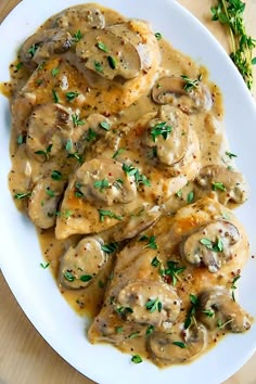 a white plate topped with chicken covered in gravy and garnished with parsley