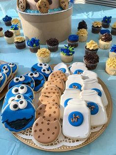 cookies and cupcakes are arranged on a table with cookie monster cakes, frosting, and decorations