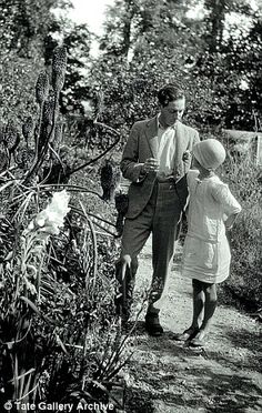 an old black and white photo of two people walking down a path in the woods