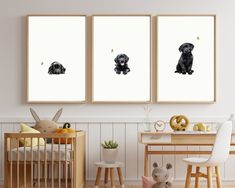 three black dogs sitting in front of a baby's crib