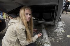 a young woman is looking under the hood of a car that has it's door open