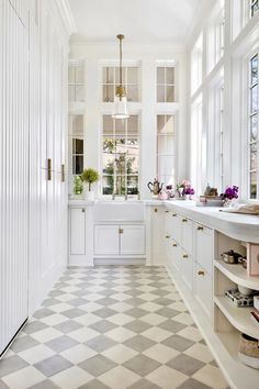 a white kitchen with checkered flooring and lots of window sill on the side