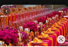 a long table is set with orange and pink flowers, wine glasses, and plates