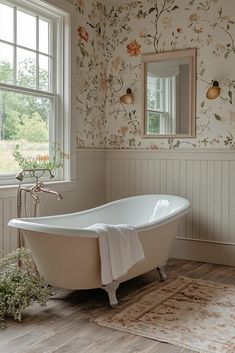 a bath tub sitting next to a window in a room with flowers on the wall