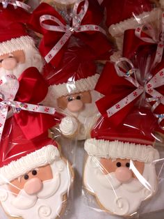 santa cookies are wrapped in plastic and have red bows on their heads as they sit next to each other