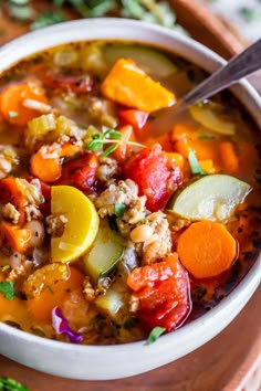 a white bowl filled with soup on top of a wooden cutting board next to a spoon