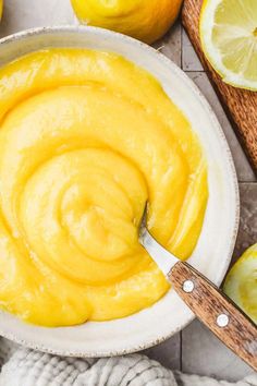 a bowl filled with lemon curd next to sliced lemons