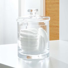 a glass container filled with white towels on top of a counter