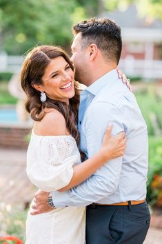 a man and woman hugging each other in front of flowers