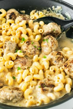 a skillet filled with macaroni and cheese, meatballs and gravy