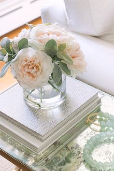 a glass vase filled with flowers sitting on top of a table next to a white couch