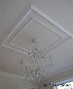 a chandelier hanging from the ceiling in a room with white walls and windows