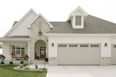 a white house with two car garages on the front and one door is open