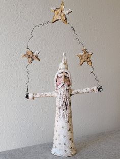 a small white statue with stars on it's head and hands in the shape of a wizard