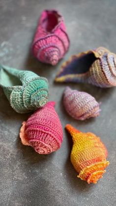 several small knitted shells sitting on top of a cement floor next to each other