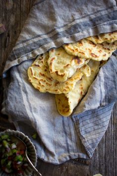 several flatbreads are on a towel next to a bowl of salad