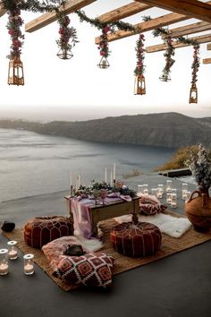 an outdoor dining area with candles and decorations on the table, overlooking water in the distance