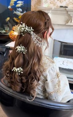 a woman with long hair sitting in a chair wearing a tiara and flowers on her head