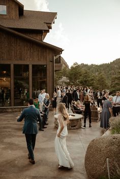 a bride and groom walk through the courtyard at their rustic outdoor wedding reception in colorado