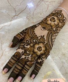 henna tattoo on the palm of a woman's hand with flowers and leaves