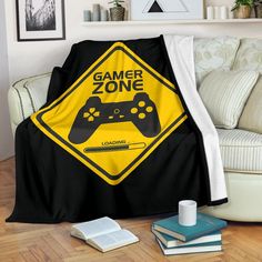 a black and yellow blanket with a video game zone crossing sign on it next to a couch