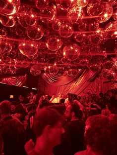 a large group of people in a room with disco balls hanging from the ceiling and lights on the ceiling