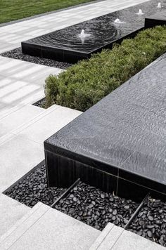 an outdoor water feature in the middle of a walkway with grass and rocks around it