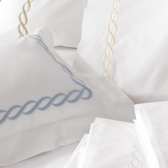 white pillows with blue thread on them and two pillow cases next to eachother