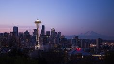 the seattle skyline is lit up at night with the space needle in the foreground