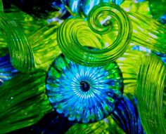 an abstract image of blue and green swirls in glass art work on display at the museum