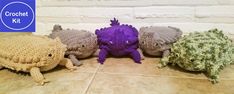 four crocheted stuffed animals sitting next to each other on a tile floor in front of a brick wall