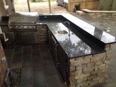 an outdoor kitchen with black granite counter tops