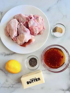 ingredients to make chicken wings on a white plate next to lemons and seasoning