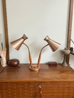 two brass lamps sitting on top of a wooden dresser