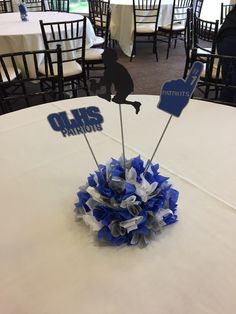 a centerpiece on top of a table with blue and white pom poms