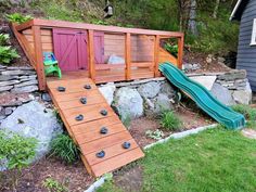 an outdoor play area made out of rocks and wood with a slide in the middle