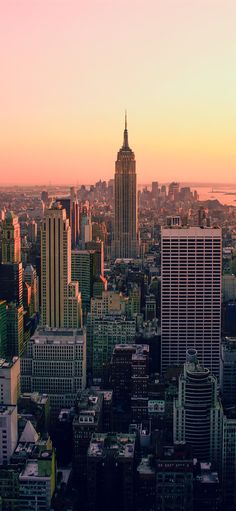 an aerial view of the city with skyscrapers and water in the background at sunset