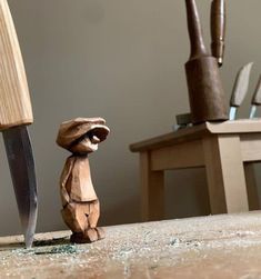 a wooden toy standing next to a knife on top of a table in front of a chair