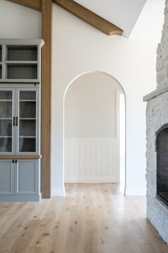 an empty living room with a fireplace and built in bookcases