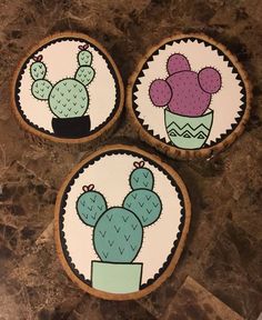 three decorated cookies sitting on top of a counter next to each other with cactus designs